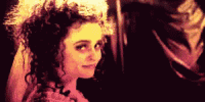 a woman with curly hair and a flower in her hair is looking at a man .