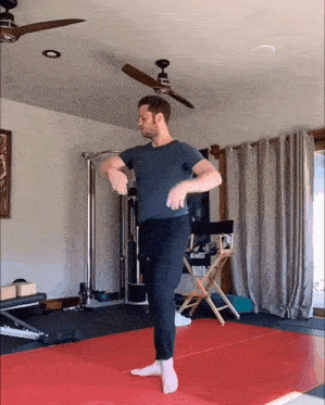 a man in a blue shirt is standing on a red mat