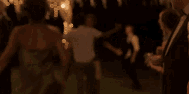 a group of people are dancing on the grass at night