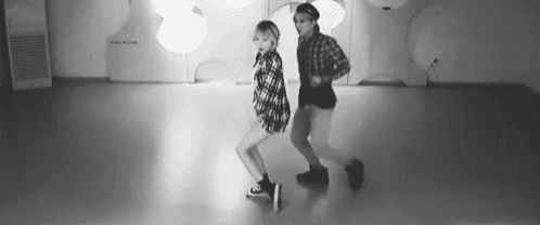 a black and white photo of two women dancing together in a room .