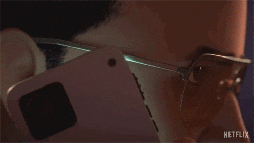a man wearing glasses is talking on a cell phone with netflix written on the bottom