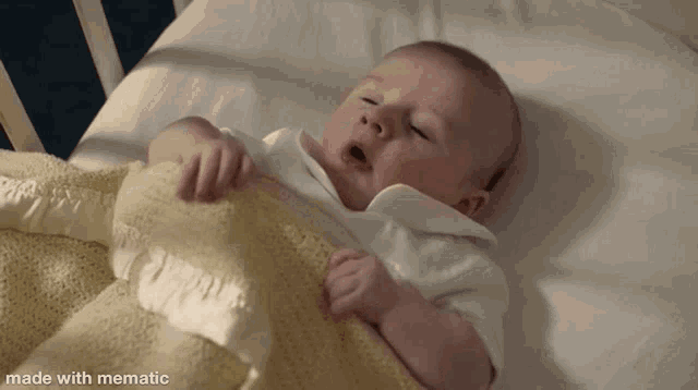 a baby is laying in a bed with a yellow blanket