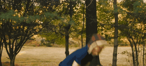 a person in a blue shirt is standing in the woods