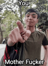 a young man is pointing at the camera while wearing a green shirt and a backpack .