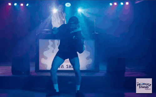 a man is dancing on stage in front of a sign that says " a sha "