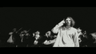 a group of people are standing in a dark room with a man playing a guitar .