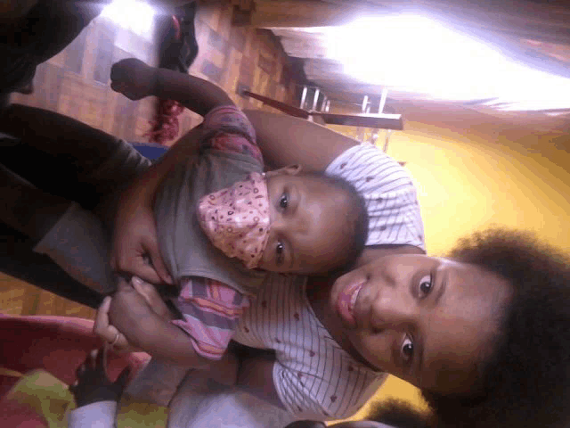 a woman is holding a baby in her arms and the baby is wearing a pink face mask