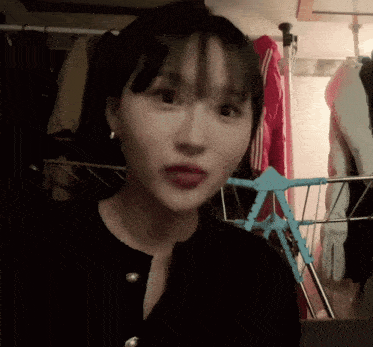 a woman stands in front of a clothes rack