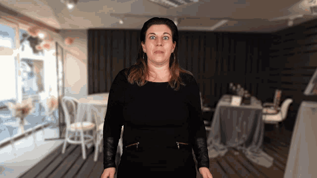 a woman in a black dress is standing in a room
