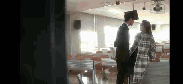 a man and a woman are standing in a lecture hall talking to each other
