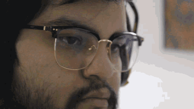 a man wearing glasses and headphones looks down at something