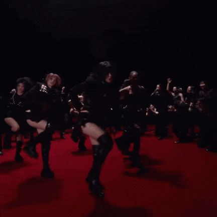 a group of women are dancing on a red carpet in front of a crowd