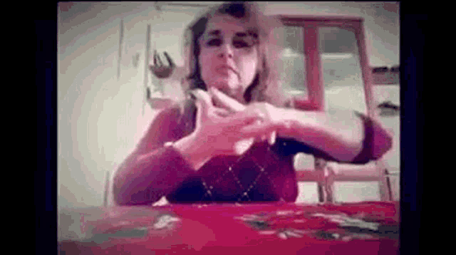 a woman is sitting at a table with her hands on her face .