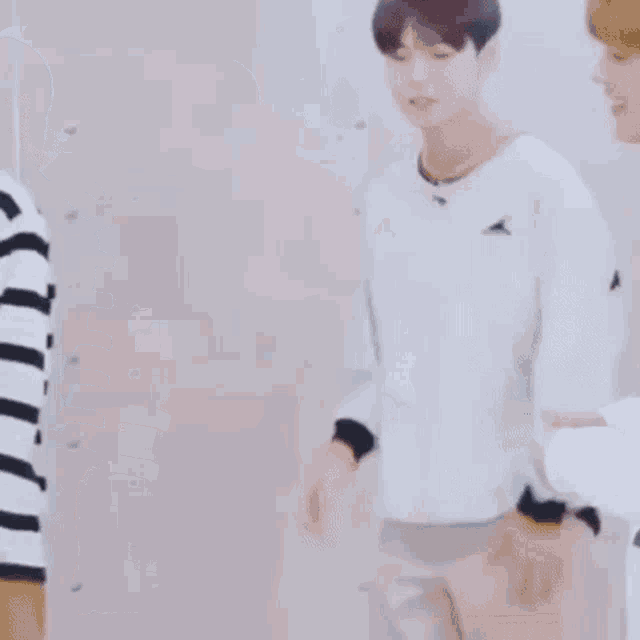 a man in a striped shirt is standing next to another man in a white sweater .