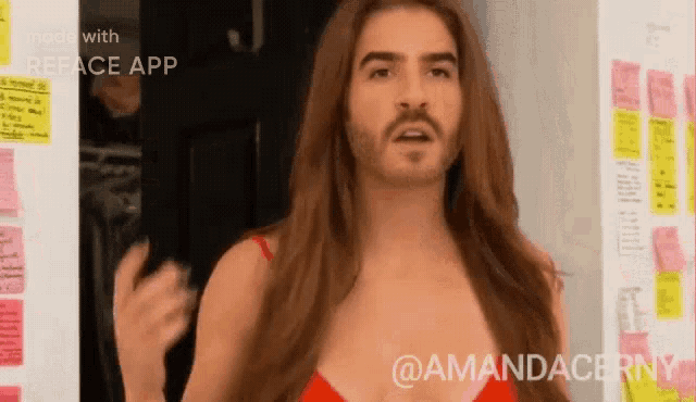 a man with a beard and long hair is wearing a red bra .