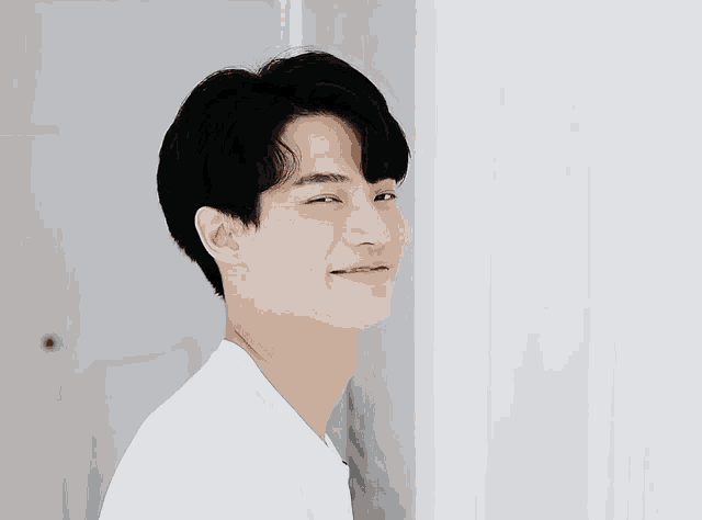 a man in a white shirt is smiling and looking to the side