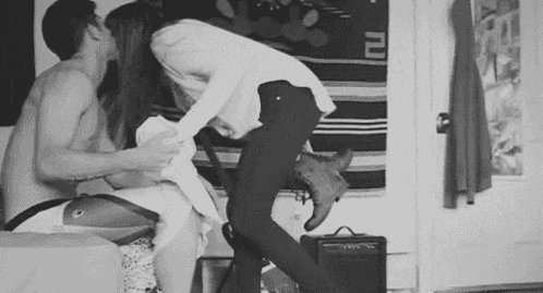 a man and a woman are kissing in a room while a woman is standing next to them .