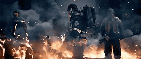 a group of firefighters are standing in front of a burning building .
