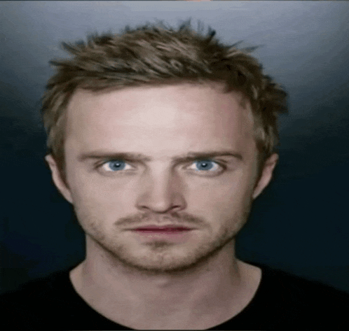 a man with blue eyes and a beard looks at the camera