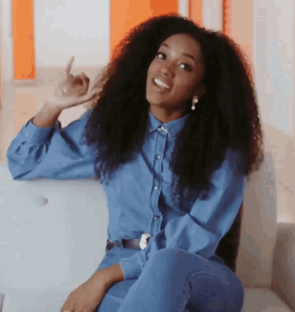 a woman in a blue shirt and jeans is sitting on a couch