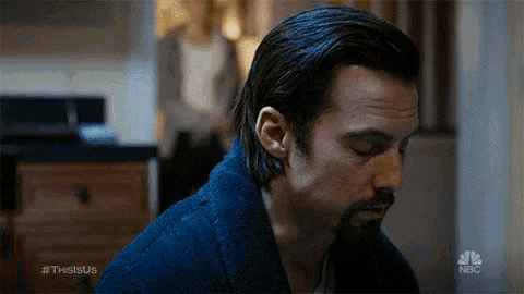 a man with long hair and a beard is wearing a blue sweater and a blue robe .