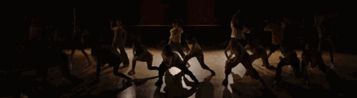 a group of people are dancing in a dark room and one of them has a shirt on that says ' a ' on it