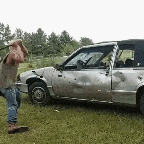 a man is standing in front of a damaged silver car