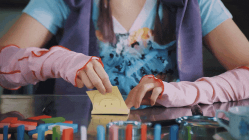 a girl wearing pink gloves holds a piece of paper with a picture of a smiley face on it