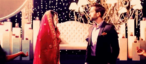 a bride and groom are standing next to each other in front of a stage .