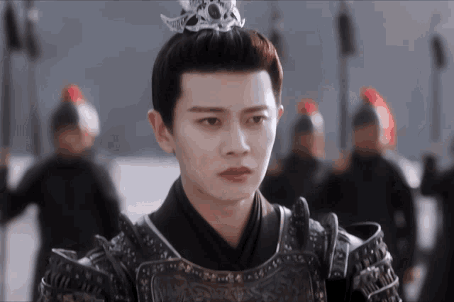 a young man wearing armor and a crown looks at the camera