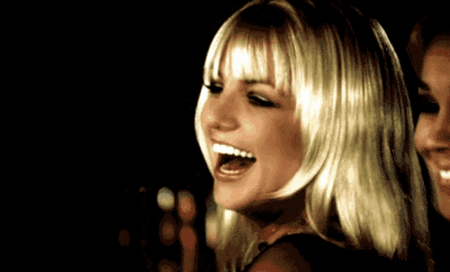 a woman with blonde hair and bangs is laughing
