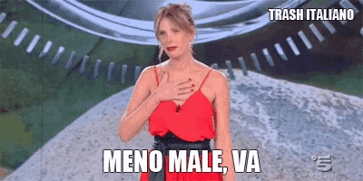 a woman in a red dress is standing in front of a clock and says meno male va