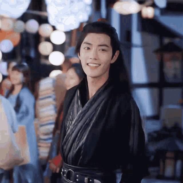 a man in a black kimono is smiling in front of a crowd of people