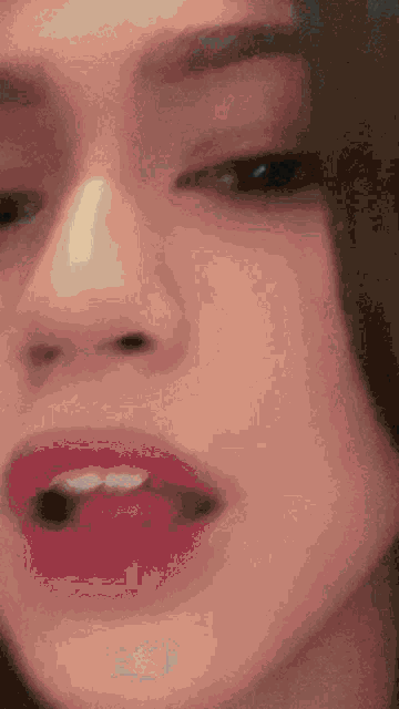 a close up of a woman 's face with red lipstick and a nose ring .