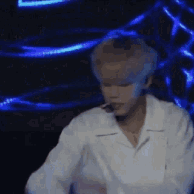a man in a white shirt is standing in front of a microphone on a stage .