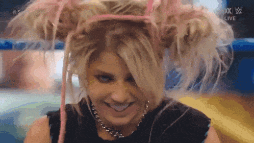 a woman wearing a headband and a necklace is smiling in a wrestling ring .