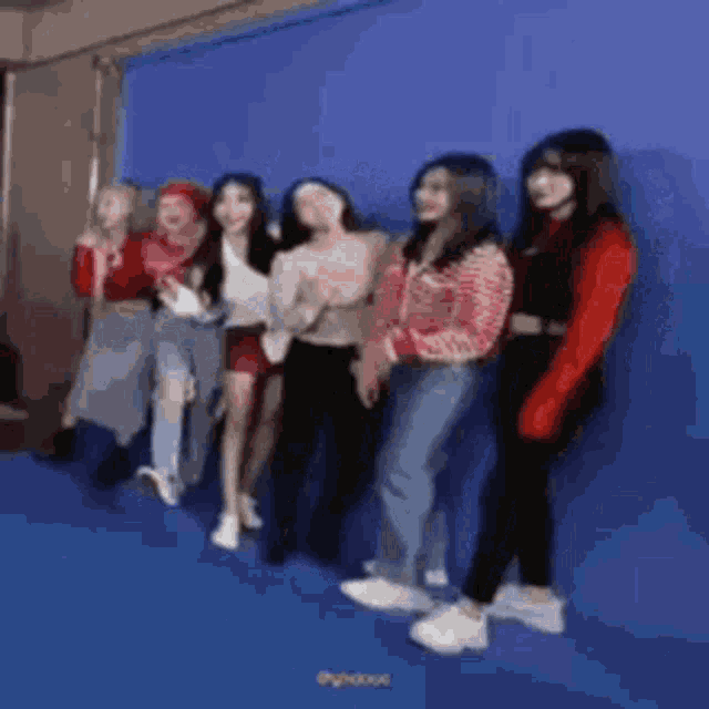 a group of women are standing next to each other in front of a blue background .
