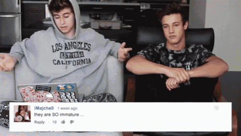 two boys are sitting on a couch with one wearing a los angeles sweatshirt