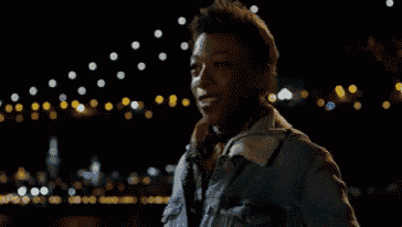 a man in a denim jacket is standing in front of a blurry background of lights