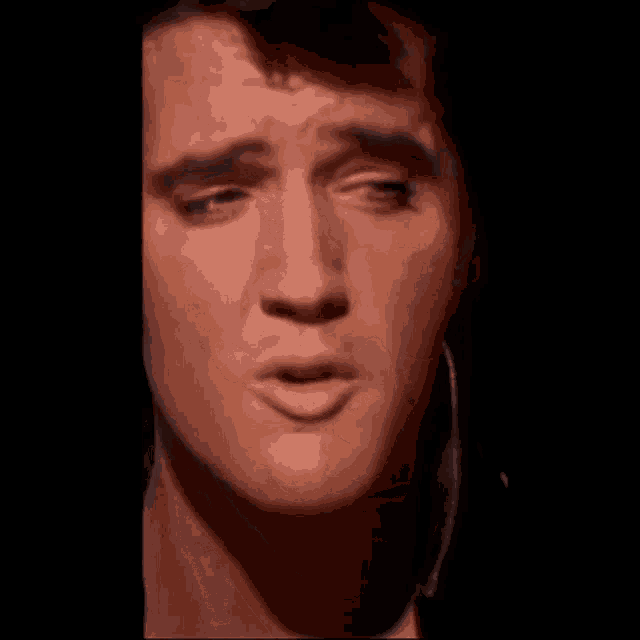 a close up of elvis presley 's face with a blue object in his mouth .