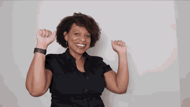 a woman in a black shirt is flexing her arms and smiling