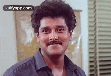 a man with a mustache is making a funny face and smiling .
