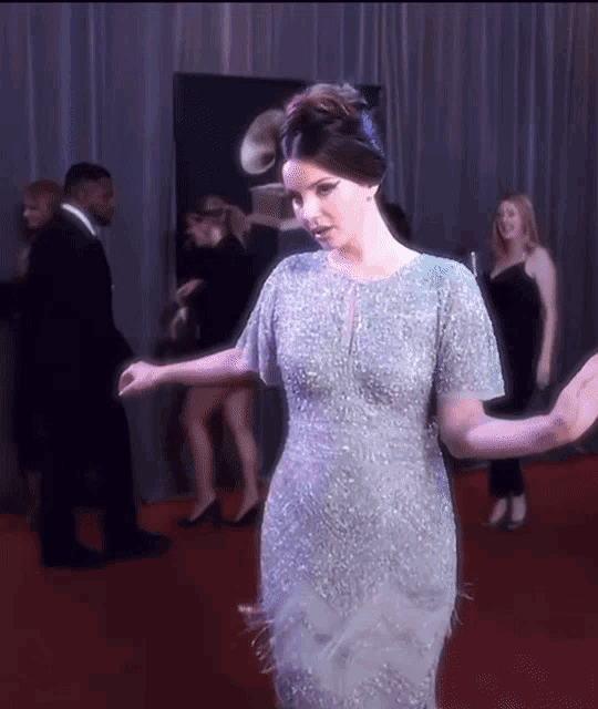 a woman in a blue dress is dancing on a red carpet