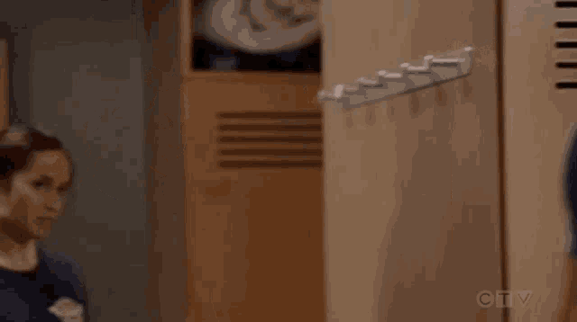 a woman is standing in a locker room next to a hanger .