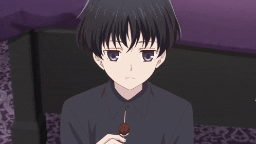 a boy with short black hair is holding a chocolate covered ball on a stick