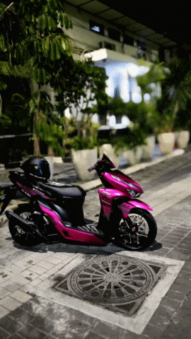 a pink and black scooter is parked on the sidewalk