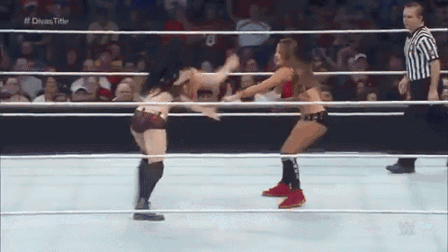 two women are wrestling in a wrestling ring with a referee watching .