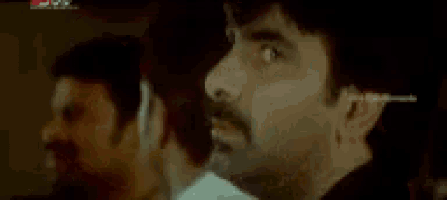 a close up of a man 's face with a reflection of another man in a mirror .