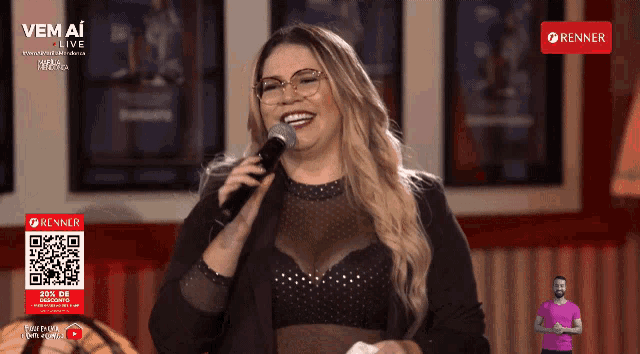 a woman singing into a microphone in front of a sign that says ' renner ' on it