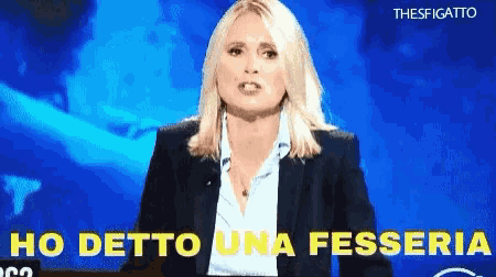 a woman in a suit stands in front of a blue background and says ho detto una fessere